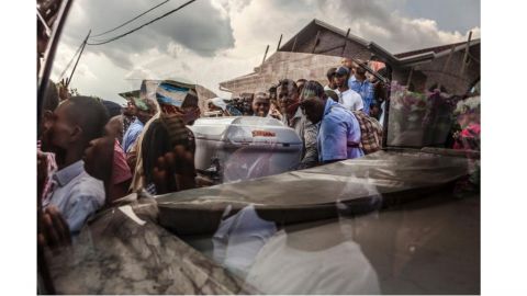 Une photo prise à travers une fenêtre montre les partisans du parti d’opposition UDPS portant le cercueil d’un militant à Kinshasa, le 31 octobre 2016, après les corps de six autres du parti d’opposition congolaise, qui ont été brûlés dans des incendies criminels dans la nuit du 19 septembre 2016 au siège de la partie, ont été libérés de la morgue